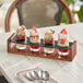 An Acopa Write-On Drop-In Flight Carrier with Straight Up Tasting Glasses holding a row of desserts in glasses on a table.