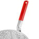 A close-up of a metal strainer with a red handle.