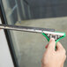 A person holding a green Unger ErgoTec SwivelLoc squeegee handle.