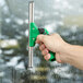 A hand holding a Unger ErgoTec SwivelLoc 0 Degree green and black squeegee handle.