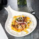 A Tuxton eggshell china fry pan server with a plate of food and a fork.