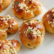 A plate of food with bread rolls and cheese next to a bowl of minced garlic on a white surface.