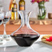 A Franmara crystal wine decanter filled with red wine on a table with wine glasses.