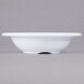 A white Carlisle melamine fruit bowl with a rim on a gray background.