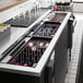 An Avantco beverage cooler on a counter in a cocktail bar with bottles inside.