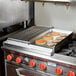 Pancakes cooking on a 24" griddle over a gas stove.