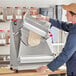 A man using an Estella countertop dough sheeter to cut dough.