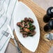 A white porcelain bowl filled with mushrooms and spinach on a table.