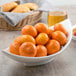 A white porcelain bowl filled with oranges.