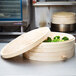 A stack of round wooden bamboo steamer covers on a table.