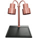 A Hanson Heat Lamps bright copper carving station with dual lamp posts on a black surface.