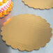 A close-up of a cake on a gold laminated corrugated cake circle with a scalloped edge.