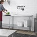 A woman using a Regency stainless steel work table with an undershelf in a kitchen.