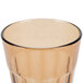 A close up of a Cambro Newport amber plastic tumbler with a rim.