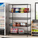 Regency black wire shelving with baskets and snacks on a shelf in a convenience store.