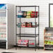 Regency black wire shelving with baskets and a shelf holding snacks and drinks in a convenience store.