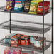 A Regency black metal shelf with snacks on it.