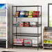 Regency black wire shelving with baskets and a shelf holding snacks and drinks in a convenience store.