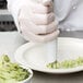 A hand in a white glove using a white Ateco polyurethane coated pastry bag to decorate food.