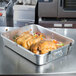 A Vollrath aluminum roaster pan with a roast chicken.