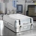 A Vollrath aluminum roaster pan with metal handles sitting on a counter.