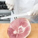 A chef in white gloves using a Dexter-Russell Sani-Safe Narrow Duo-Edge Slicer to cut meat.