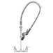 A chrome T&S wall mounted pre-rinse faucet with a curved hose.