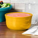 A yellow Fiesta china gusto bowl filled with pink food on a table.
