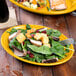 A Fiesta Daffodil china platter with salad and a fork on a table.