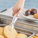 A hand using Cambro clear plastic tongs to serve a stack of pancakes.