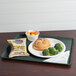 A Cambro slate blue hospital dietary tray with a sandwich, broccoli, and potato chips.