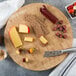 An American Metalcraft bamboo cutting board with cheese and crackers on a table.