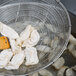 A Town stainless steel round skimmer with a bamboo handle used to remove dumplings from a pot.