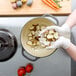 A person in gloves putting potatoes in a Lodge enameled cast iron Dutch oven.