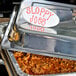 A white American Metalcraft oval ceramic card sign with red writing that says "sloppy joes" on a tray of food.