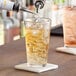 A bartender pouring a drink from a liquid dispenser into an Acopa pint glass.