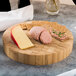 An American Metalcraft bamboo cutting board with cheese, crackers, and meat.