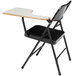 A black National Public Seating folding chair with a left gray tablet arm on a white table.