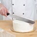 A person using an Ateco straight baking spatula to cut a cake.