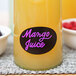 A Franmara neon purple glass marker on a glass of yellow liquid with a black label.