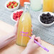 A person using a Franmara neon purple mini tip glass marker to write on a bottle of yellow liquid.