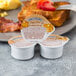 A plate with breakfast and bacon with two open portion cups of Smucker's Sugar Free Breakfast Syrup on it.