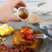 A person pouring Smucker's Sugar Free Breakfast Syrup on a plate of french toast.