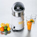 A Waring citrus juicer with a bowl of oranges, lemons, and limes.