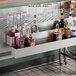A 42-inch Steelton stainless steel double tier speed rail holding various liquor bottles in a bar setting.