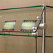 A glass sneeze guard with signs on a glass shelf.