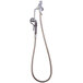 A T&amp;S wall mounted metal hose attached to a wall with a hook nozzle.