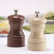 A wooden pepper mill and salt mill set on a table.