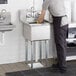 A man standing at a Regency stainless steel commercial sink in a professional kitchen.