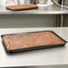 A Solut black half size paperboard sheet pan of brownies.